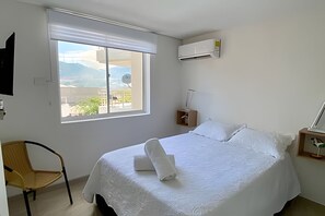 Ein Hotelzimmer mit Bett, Stuhl, Fenster und Klimaanlage.