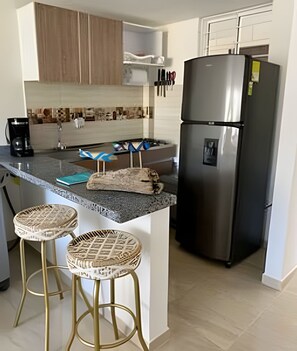 Eine Küche mit einem Edelstahlkühlschrank, einer Kaffeemaschine und zwei Weidenbarhocker.