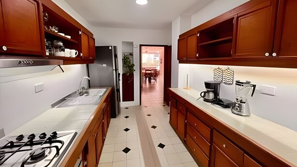 A kitchen with wooden cabinets, a gas stove, a refrigerator, and a coffee maker. - Enjoy Rodadero 1 Block to Beach | 3BR 3BA Fits 10 (Santa Marta)