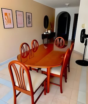 A dining area with a wooden table and chairs, framed artwork on the wall, and a mirror. - Enjoy Rodadero 1 Block to Beach | 3BR 3BA Fits 10 (Santa Marta)