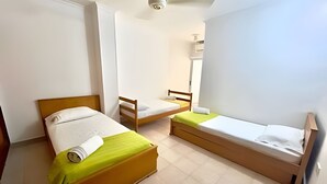 A room with two beds, a wooden headboard, a small table, and a mirror. - Enjoy Rodadero 1 Block to Beach | 3BR 3BA Fits 10 (Santa Marta)