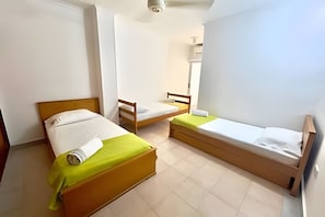 A room with two beds, a wooden headboard, a small table, and a mirror. - Enjoy Rodadero 1 Block to Beach | 3BR 3BA Fits 10 (Santa Marta)