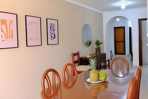A dining area with a glass table, wooden chairs, and framed artwork on the wall. - Enjoy Rodadero 1 Block to Beach | 3BR 3BA Fits 10 (Santa Marta)