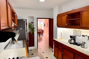 A kitchen with wooden cabinets, a refrigerator, a coffee maker, and a plant. - Enjoy Rodadero 1 Block to Beach | 3BR 3BA Fits 10 (Santa Marta)