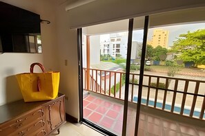 A room with a sliding glass door leading to a balcony with a view of buildings and greenery. - Spacious Beach House Bello Horizonte Pool & Beach (Santa Marta)