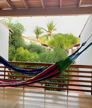 A hammock in a covered outdoor area with a view of a garden and buildings. - Spacious Beach House Bello Horizonte Pool & Beach (Santa Marta)