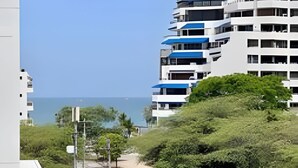 A coastal residential area with modern buildings, a clear sky, and a pathway leading to the beach. - Bello Horizonte Haven | Resort Pools & Beach (Santa Marta)