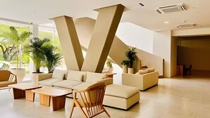 A modern lobby with a V-shaped architectural feature, a seating area with sofas and chairs, and potted plants. - Bello Horizonte Haven | Resort Pools & Beach (Santa Marta)