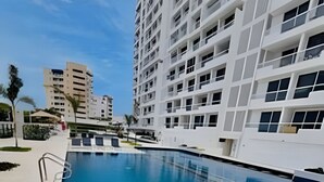 A swimming pool with clear blue water, surrounded by modern buildings. - Bello Horizonte Haven | Resort Pools & Beach (Santa Marta)