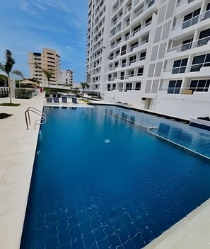 Uma piscina com água azul cristalina, rodeada por edifícios modernos.