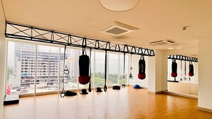 A spacious room with large windows, a wooden floor, and a ceiling-mounted punching bag.