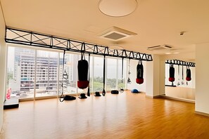 A spacious room with large windows, a wooden floor, and a ceiling-mounted punching bag.