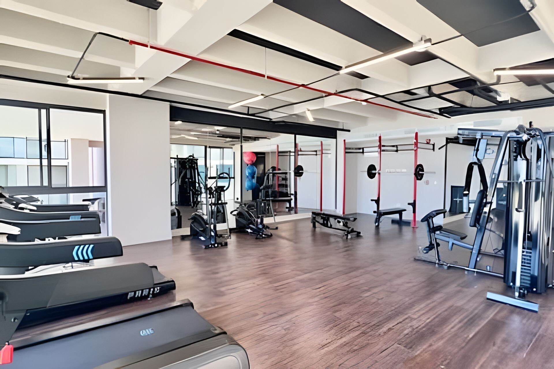 Une salle de sport équipée de tapis de course, d’appareils de musculation et d’un mur recouvert de miroirs.