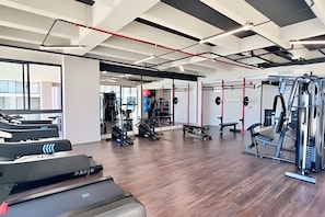 A gym with treadmills, weight machines, and a mirrored wall.