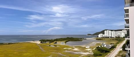 A coastal view with a building complex, a beach, and a body of water.
