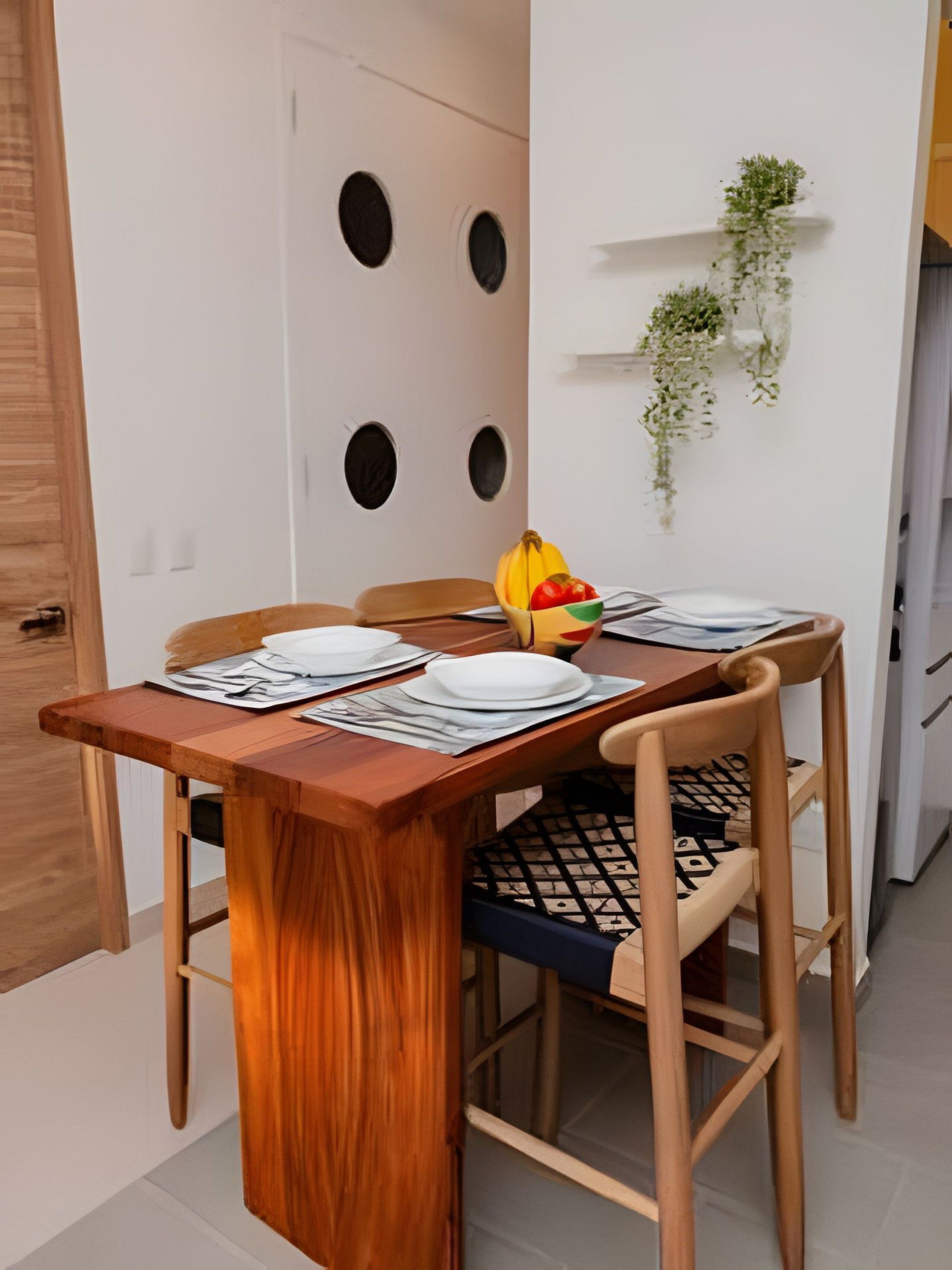 A dining table with plates, a bowl of fruit, and a chair with a patterned cushion.