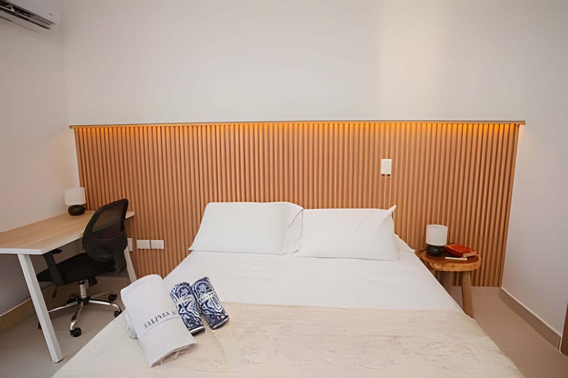 Et hotelværelse med en seng, et skrivebord og en stol.