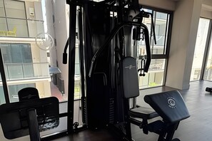 Ein Fitnessstudio mit Langhantelbank, Squat-Gestell und Kabelzug.