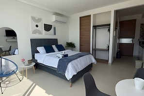 Un dormitorio moderno con una cama, mesitas de noche, una silla y una pequeña mesa.