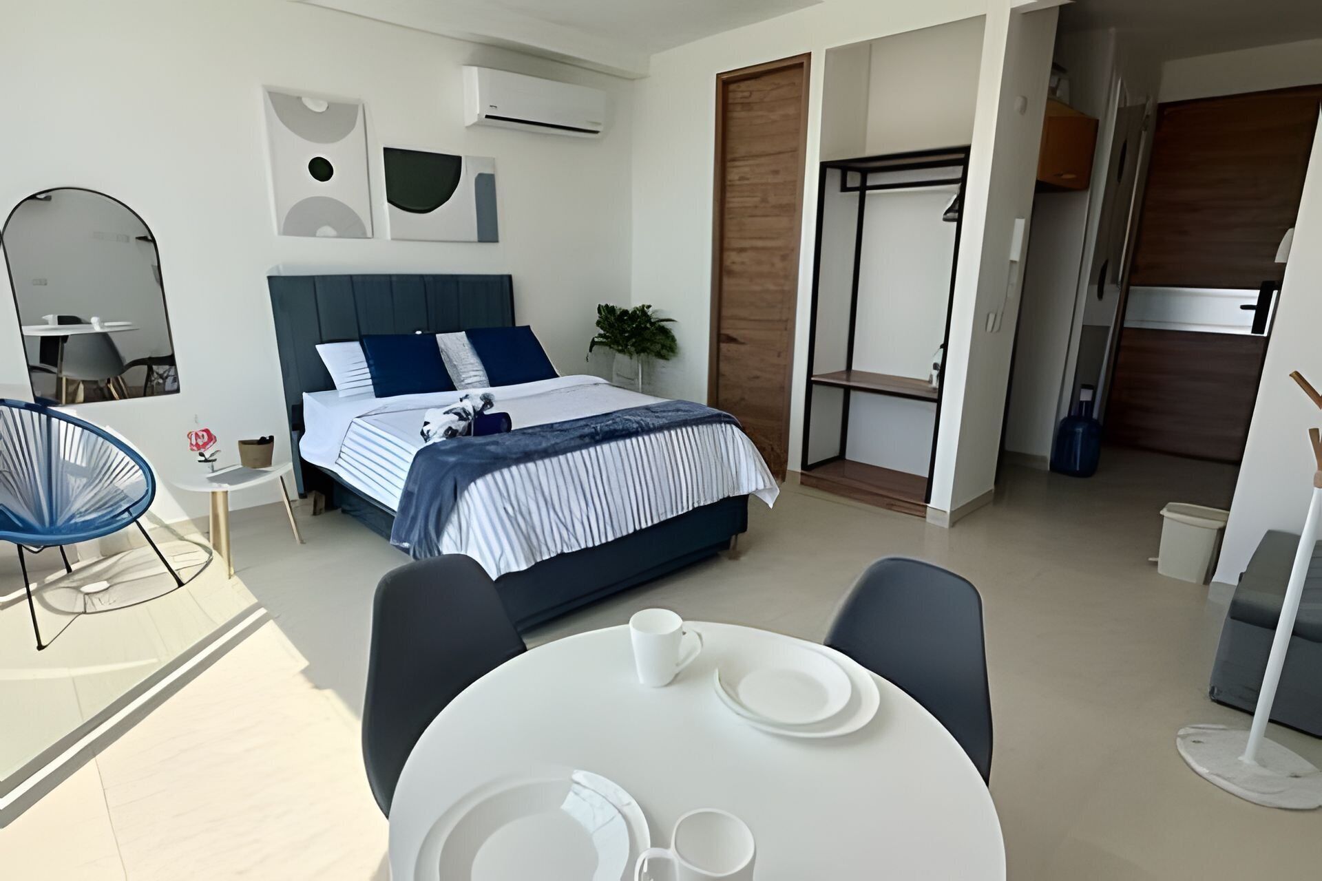 A modern bedroom with a bed, bedside table, and a dining area with a table and chairs.