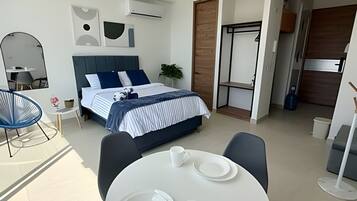 A modern bedroom with a bed, bedside table, and a dining area with a table and chairs.