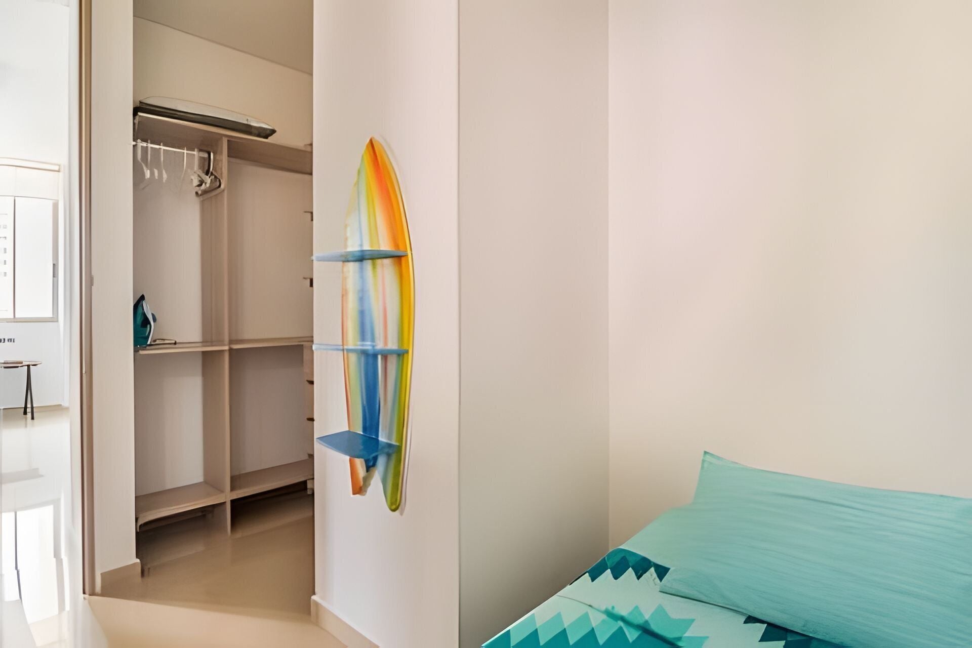 A bedroom with a bed, a closet, and a wall-mounted shelf with a colorful object.