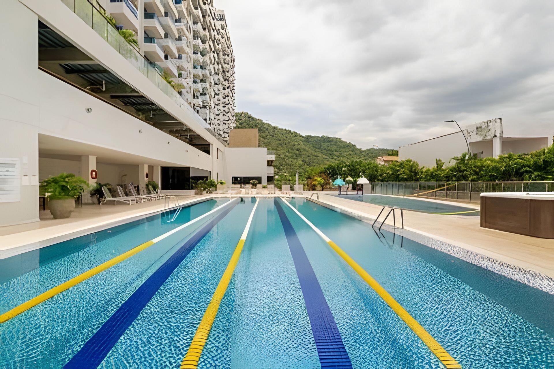 A swimming pool with clear lane markings, adjacent to a modern building with balconies.