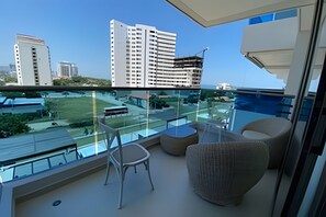 Un balcon doté d’une rambarde en verre, d’une chaise, d’une petite table et d’un canapé.