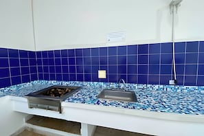 A kitchen with blue-tiled walls, a sink, and a grill. - Rodadero Escape | Pool, Balcony, BBQ & Parking (Santa Marta)