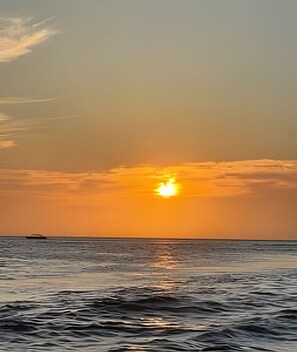 Tramonto su una distesa d'acqua con una terraferma in lontananza.