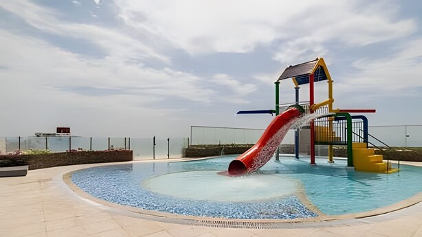 Ein Schwimmbad mit roter Rutsche und Spielplatz.