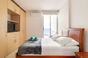 A bedroom with a bed, a TV, and a window. - Exclusive Ocean View | Playa Salguero • Sky Club (Gaira)