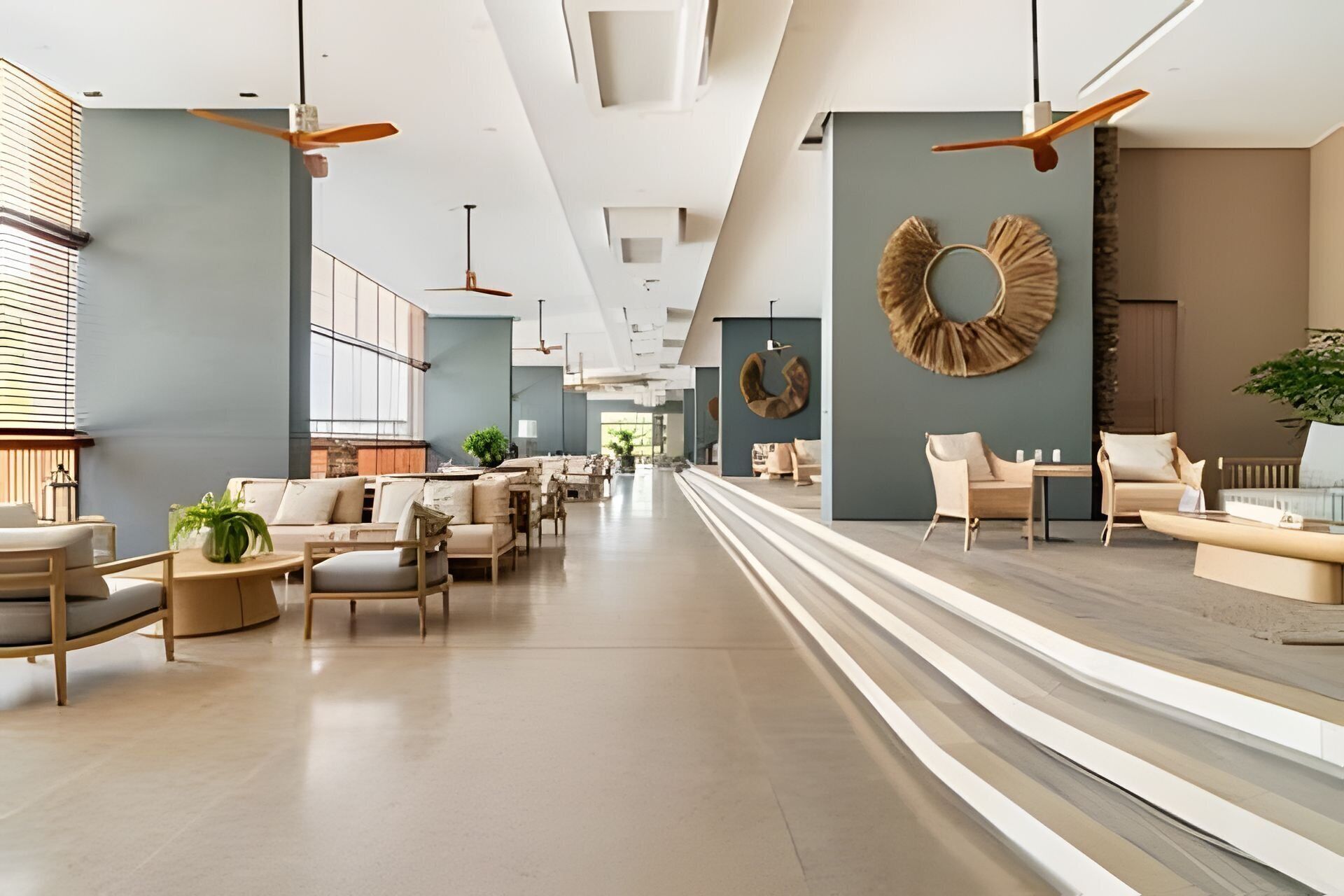 A spacious hotel lobby with modern furniture, ceiling fans, and a central seating area.
