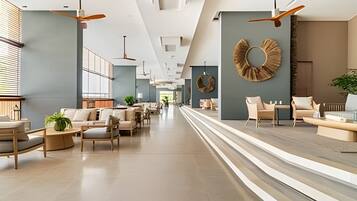 A spacious hotel lobby with modern furniture, ceiling fans, and a central seating area.
