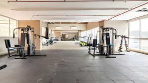 Ein geräumiges Fitnessstudio mit vielfältigen Trainingsgeräten, großen Fenstern und hoher Decke.