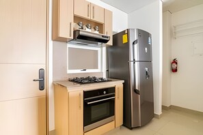A compact kitchen with a gas stove, oven, and a stainless steel refrigerator. - Exclusive Ocean View | Playa Salguero • Sky Club (Gaira)