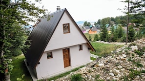 A white house with a dark roof, a wooden door, and a small window.