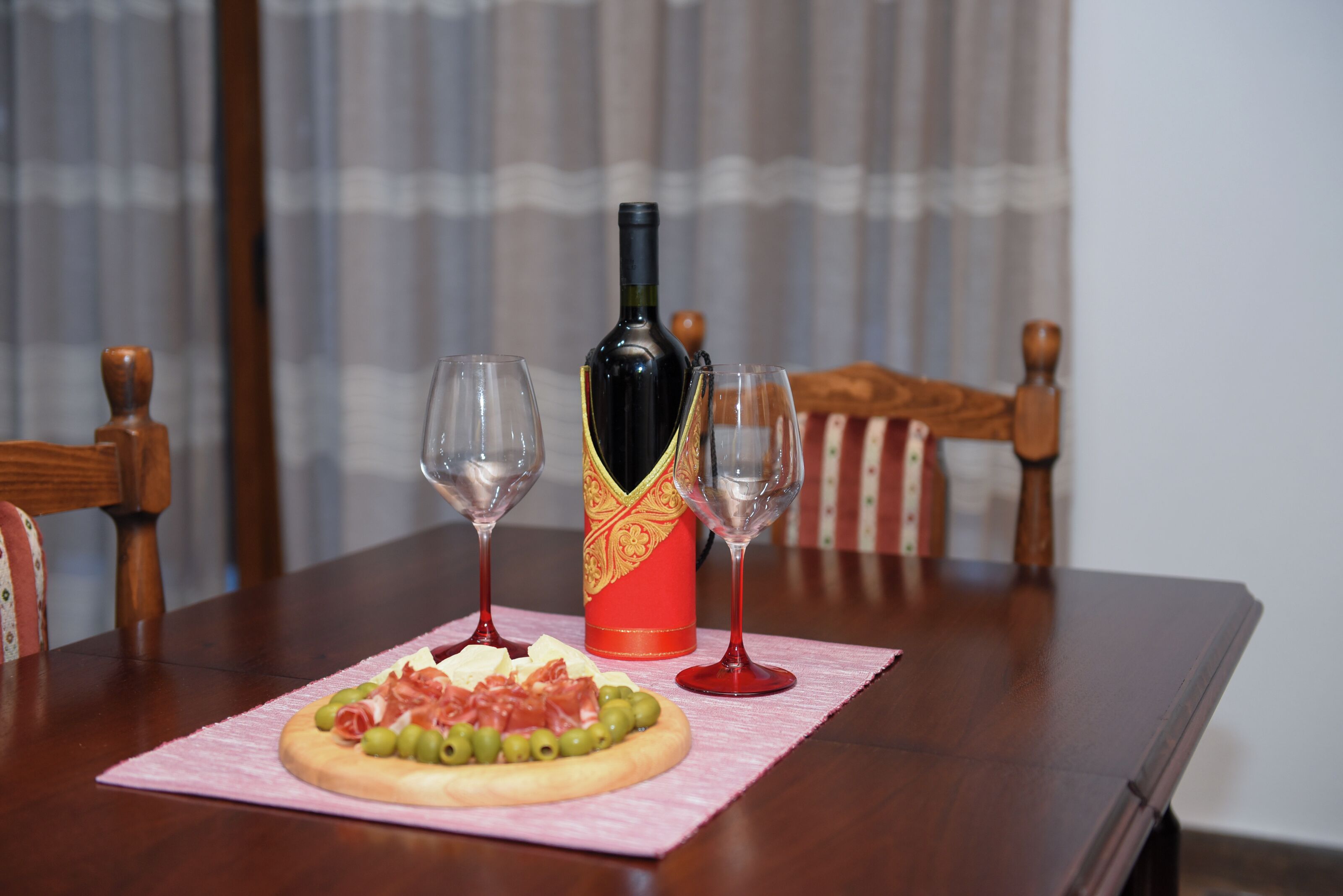 A dining table with a pizza, two wine glasses, and a bottle of wine.