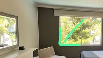 A room with a bed, a desk, and two windows.
