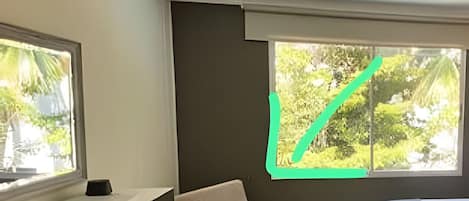 Una habitación con cama, escritorio y dos ventanas.