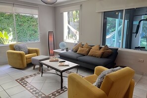 A modern living room with a sofa, armchairs, a coffee table, and a floor lamp.