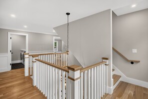 Ein modernes Interieur mit einer Holztreppe, weißen Geländern und einer hellgrauen Wand.