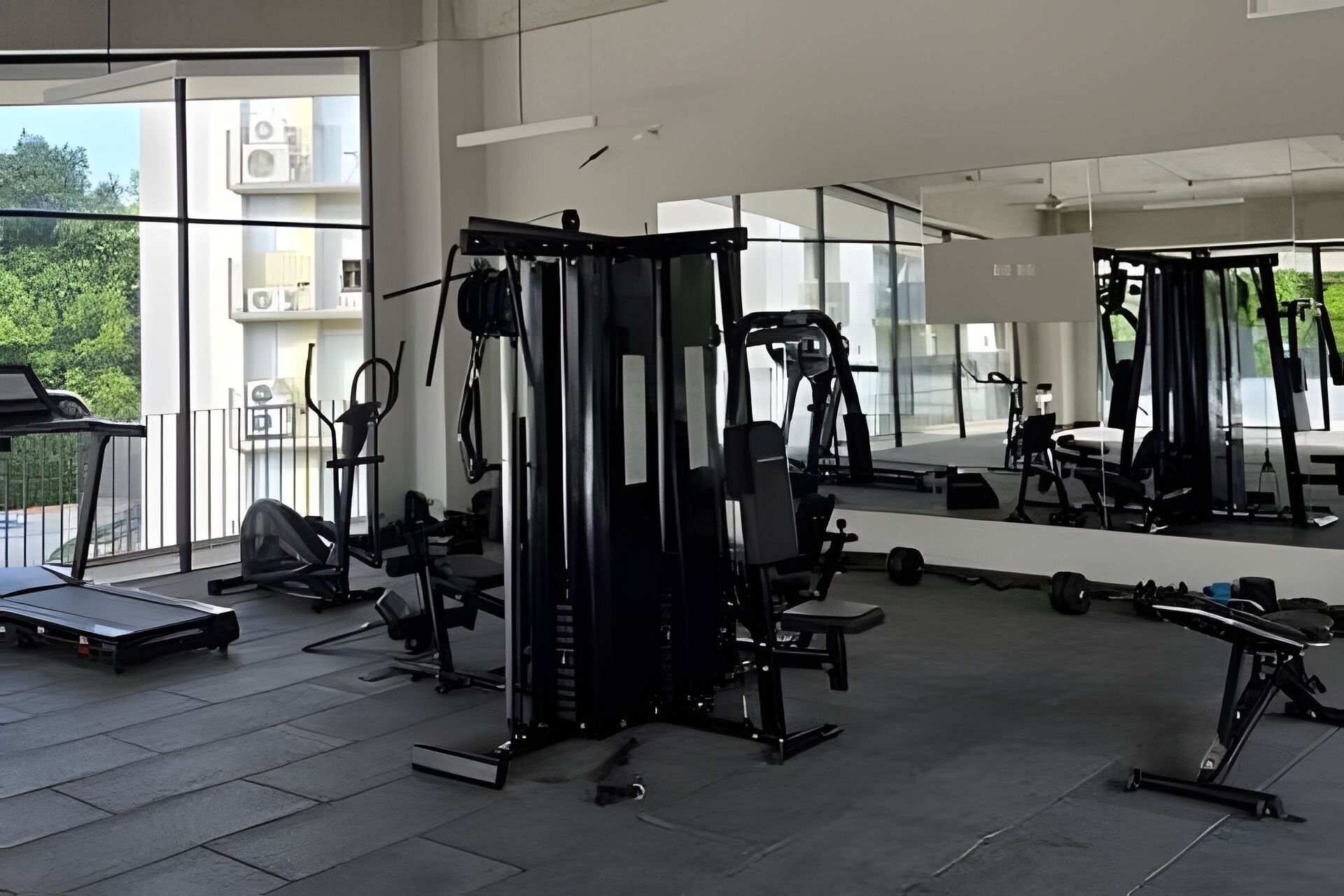 Une salle de sport équipée de divers appareils d’exercice, dotée de grandes fenêtres et offrant une vue sur l’extérieur.
