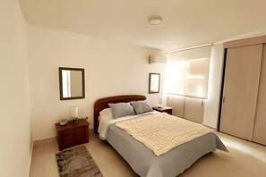 A bedroom with a bed, nightstands, a mirror, and a wardrobe. - Rodadero: Apt w/ Balcony, Ocean View & Elevator (Santa Marta)