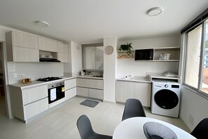 A compact kitchen with a stove, microwave, and built-in washing machine. - Rodadero: Apt w/ Balcony, Ocean View & Elevator (Santa Marta)