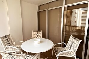 A small round table with a white bowl, surrounded by four white wicker chairs, in a room with a large sliding glass door. - Rodadero: Apt w/ Balcony, Ocean View & Elevator (Santa Marta)