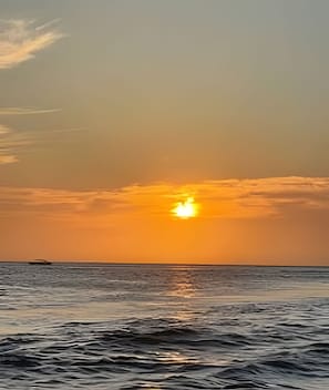 A sunset over a body of water with a distant landmass. - Rodadero: Apt w/ Balcony, Ocean View & Elevator (Santa Marta)