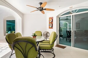 A dining area with a table, chairs, a ceiling fan, and a glass door leading outside. - Relax: Beach House w/ Private Pool & Sea Access (Santa Marta)