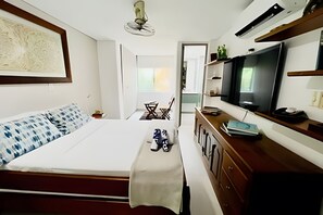 A bedroom with a bed, bedside table, TV, and a view of the outside.
