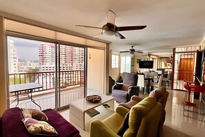 Un salon spacieux avec balcon, un coin repas et un téléviseur.
